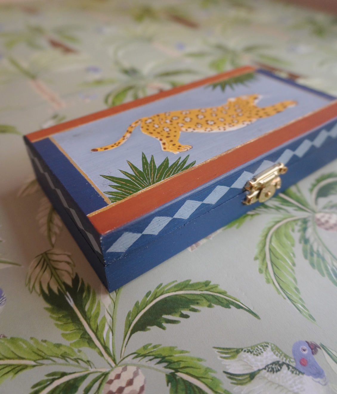 Decorative box with a jaguar design on a patterned surface